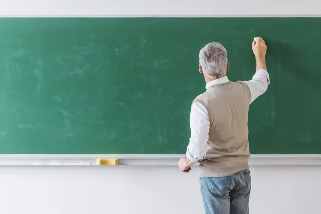 Male teacher writing on a blackboard.